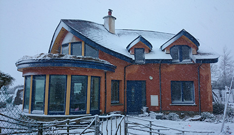 front of the mud and wood house in snow